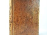 an old brown book sitting on top of a white surface