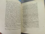 someone is holding a book open on a table with a blue background