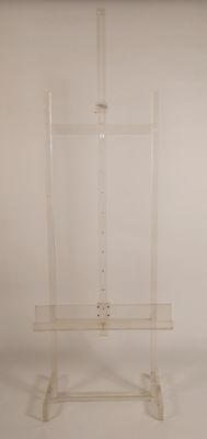 un chevalet en acrylique transparent posé sur un socle, adossé à un mur blanc