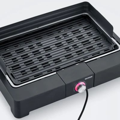 un gros plan d'un gril posé sur une surface blanche, avec un bouton rose