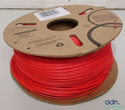 a reel of red pla filamant on a white surface