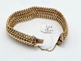 a close up of a gold bracelet on a white surface