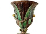 un vase vert et marron posé sur une surface blanche