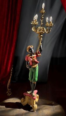 une statue représentant une femme tenant un chandelier devant un rideau rouge