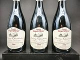 trois bouteilles de vin rouge sont posées sur une boîte noire