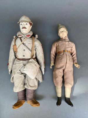 paire de poupées anciennes représentant deux hommes en uniforme militaire, posées sur un support gris