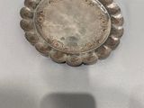un vieux plat en argent posé sur une nappe blanche