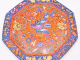 an orange and blue plate with a bird and flowers design on it