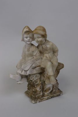 figurine représentant un garçon et une fille assis sur une souche d'arbre