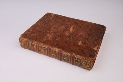 un vieux livre posé sur une table sur une surface blanche