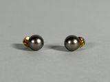 a pair of black pearl earrings on a gray surface