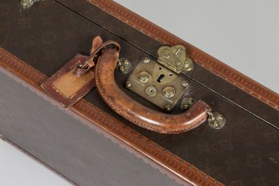 une valise marron sur laquelle est posé un cadenas