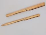 deux stylos dorés et un stylo à bille posés sur une surface blanche