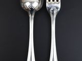 two silver spoons and a fork on a black table