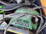 a green and black electric sander sitting on top of a black box