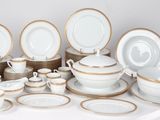 a lot of white and gold plates and bowls on a table