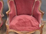 pair of red velveted chairs with carved wood legs and arms