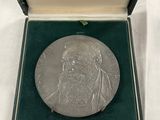 une image représentant une médaille d'argent dans un coffret posé sur une surface blanche