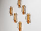 six appliques murales en verre sont disposées sur un mur blanc