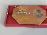 a picture of a gold tie bar in a red box