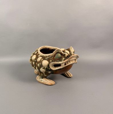une petite grenouille en céramique au long cou et aux longues pattes