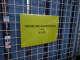 a yellow sign on a metal fence that says doublure antistatiqueque
