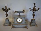 three different types of clocks and candelabs on the table