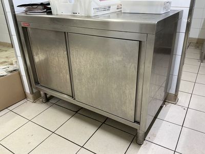 a stainless steel cabinet in the middle of a tiled floor
