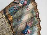 a fan with a painting on it hanging on a wall