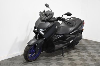 une moto noire garée dans une pièce au sol en damier