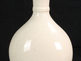 un vase blanc posé sur un fond noir