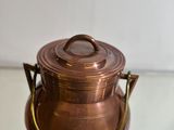 a small copper pot sitting on top of a glass table