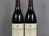 two bottles of red wine sitting on top of a glass table