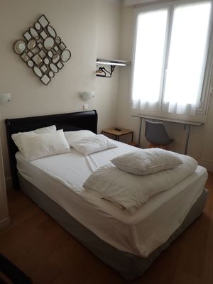 un lit avec des draps et des oreillers blancs dans une petite pièce