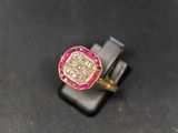 un gros plan d'une bague en or sertie de pierres roses sur un fond noir