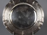an antique silver plate on a stand on a gray background