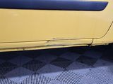 a close up of a yellow truck with a black tire
