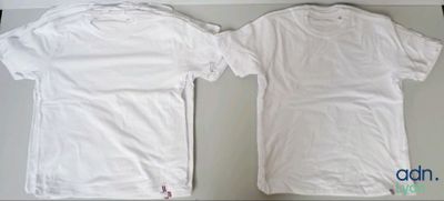 two white t - shirts sitting on top of a table next to each other