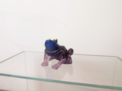 une figurine représentant une grenouille assise sur une table en verre