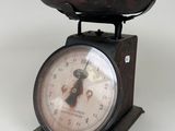 a small scale with a clock on it on a white surface