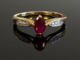 an oval ruby and diamond ring on a reflective surface