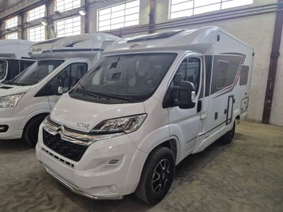 trois camping-cars blancs garés dans un entrepôt avec d'autres véhicules