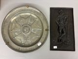 une assiette en argent sur laquelle est représenté un homme et une plaque ornée d'une étoile
