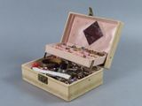 une petite boîte en bois remplie de bijoux, posée sur une surface grise