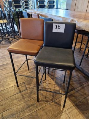 trois tabourets de bar en cuir avec une étiquette de prix dans un magasin