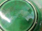 a green glass bowl with a stamp on it