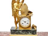 a gold statue of an angel holding a clock on a marble table