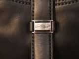 the back of a black leather purse with a metal buckle