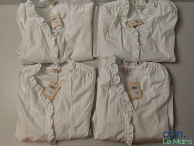 quatre paires de pyjamas blancs posées sur une table blanche