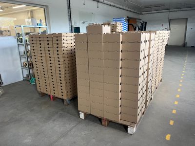 de nombreux cartons empilés sur des palettes dans un entrepôt